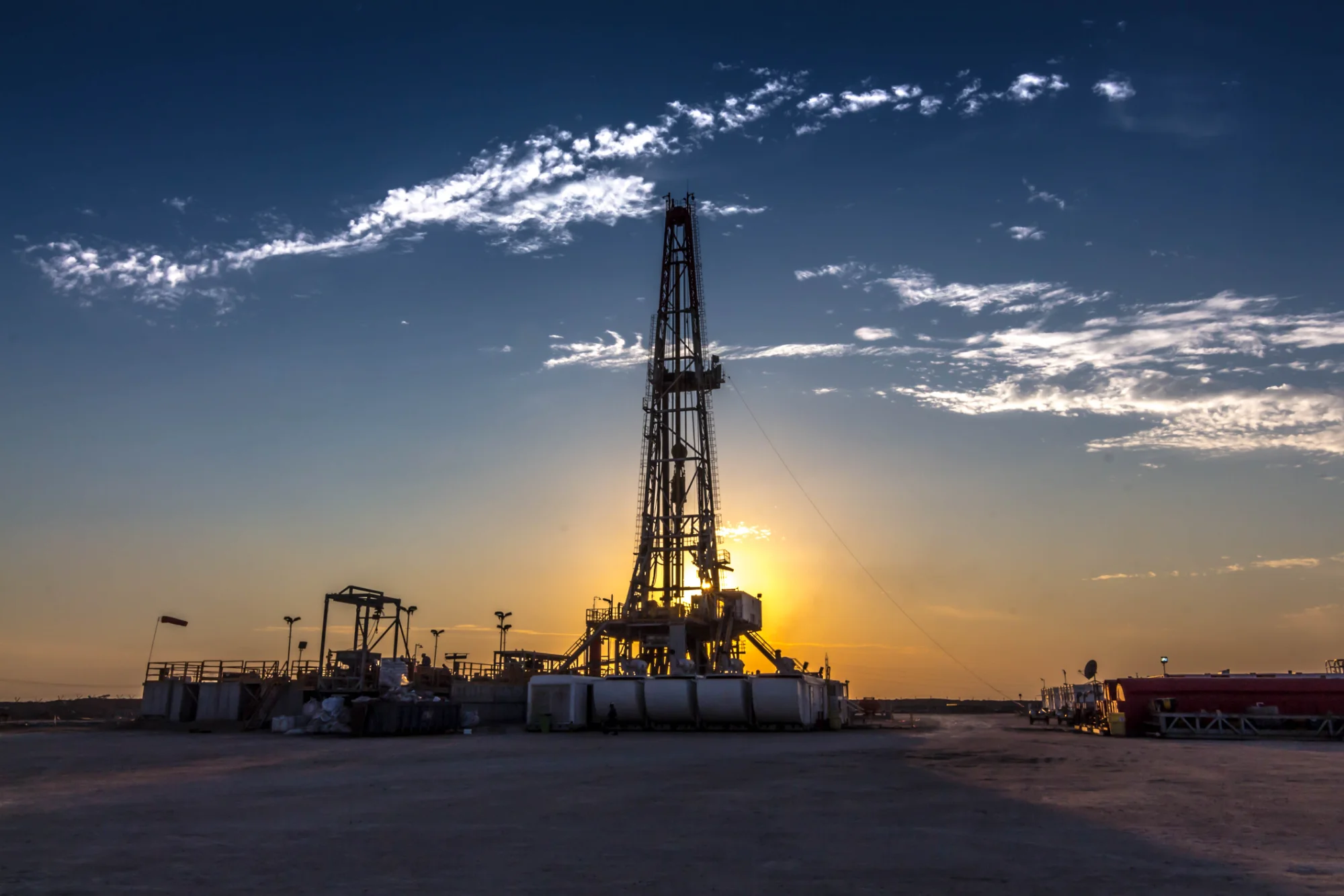 A drilling rig silhouetted against the sunset &mdash; the kind of site
                              Omni surface safety equipment is installed on.